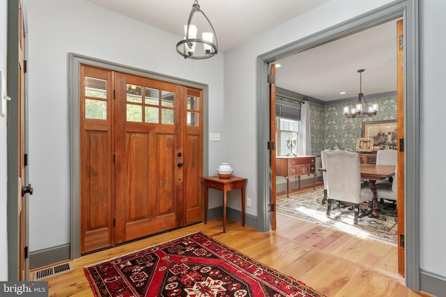 entryway with light hardwood / wood-style floors, plenty of natural light, and a chandelier