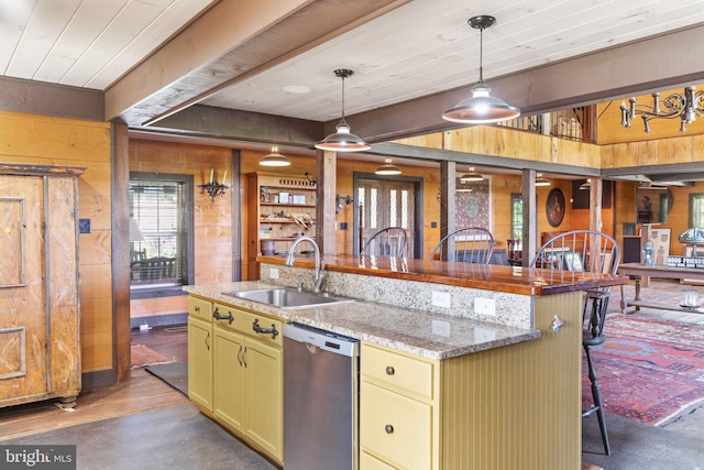 kitchen with stainless steel dishwasher, decorative light fixtures, sink, light stone counters, and a kitchen breakfast bar