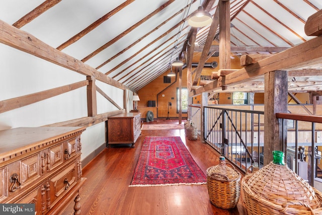 interior space with lofted ceiling with beams, wood walls, and hardwood / wood-style flooring