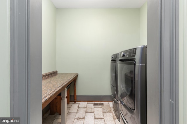 laundry area with washing machine and clothes dryer and light tile patterned floors