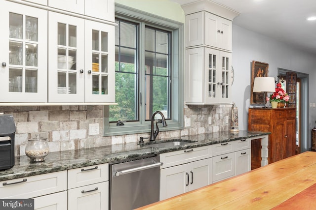 kitchen featuring dark stone counters, tasteful backsplash, white cabinets, sink, and dishwasher