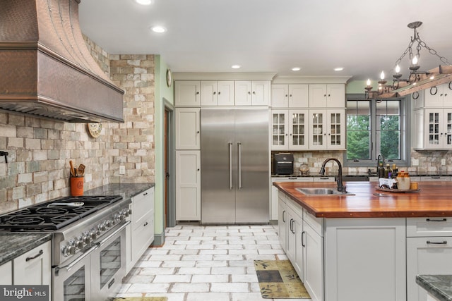 kitchen with sink, pendant lighting, premium appliances, and tasteful backsplash