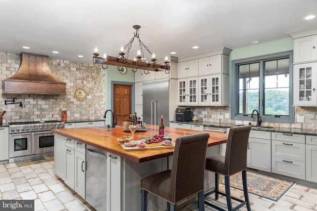 kitchen with premium appliances, butcher block counters, a center island, custom exhaust hood, and decorative backsplash