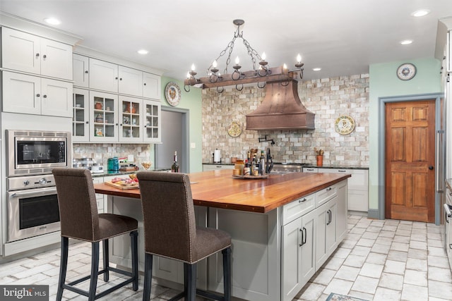 kitchen featuring tasteful backsplash, stainless steel appliances, wood counters, white cabinets, and a center island