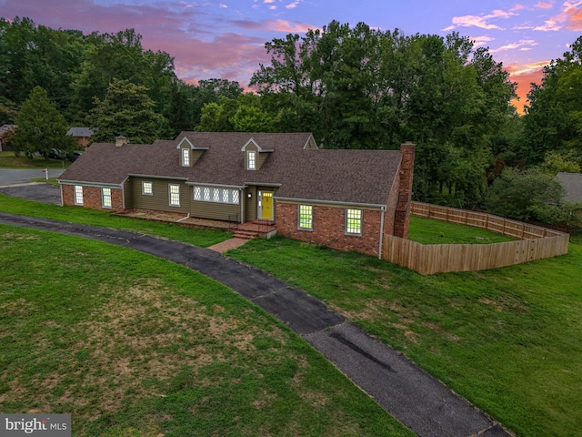 cape cod house featuring a yard