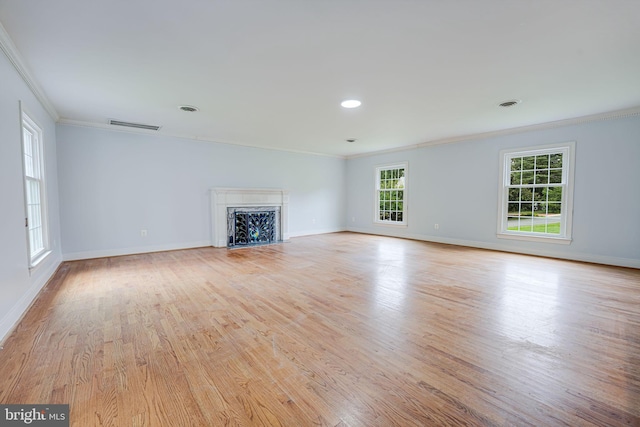 unfurnished living room featuring light hardwood / wood-style floors, a high end fireplace, and crown molding