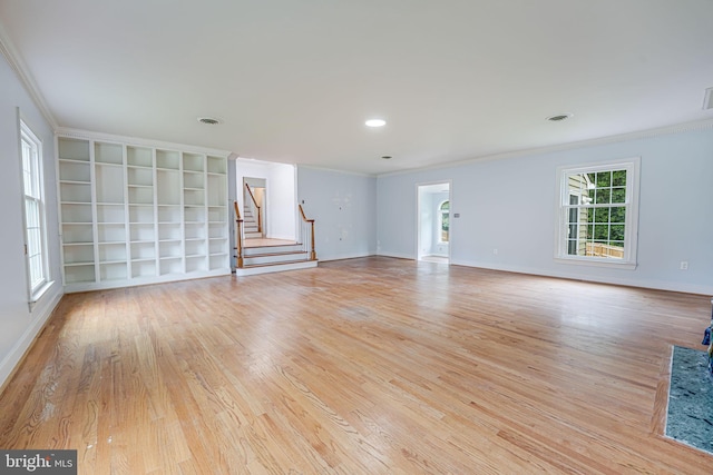 unfurnished living room with built in features, ornamental molding, and light hardwood / wood-style flooring