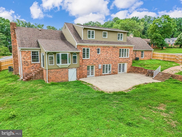 rear view of house with a lawn, cooling unit, and a patio