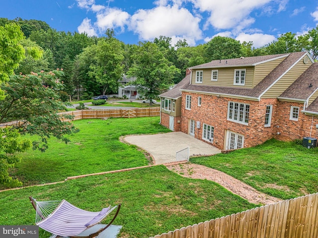 rear view of house featuring central AC unit, a patio area, and a yard