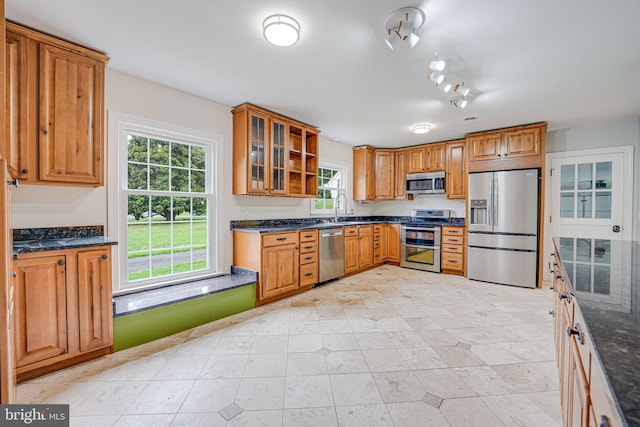 kitchen featuring a healthy amount of sunlight, dark stone counters, sink, and stainless steel appliances