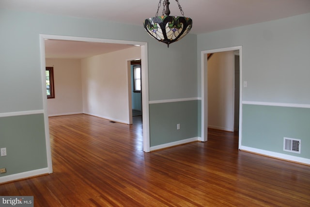 empty room featuring a chandelier and dark hardwood / wood-style flooring