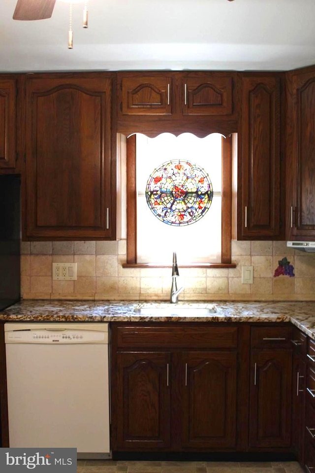 kitchen featuring sink, white dishwasher, ceiling fan, decorative backsplash, and stone countertops