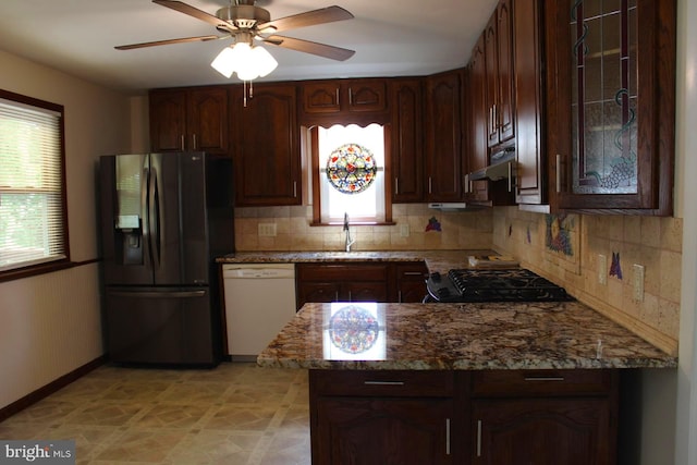 kitchen with white dishwasher, stainless steel fridge with ice dispenser, sink, ceiling fan, and light stone counters