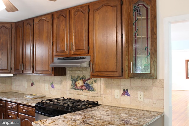 kitchen featuring black stove, ceiling fan, light stone counters, and decorative backsplash