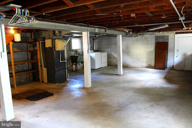 basement featuring separate washer and dryer, heating unit, and sink