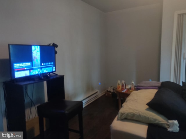 bedroom with a baseboard heating unit and wood finished floors