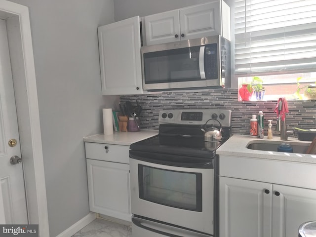 kitchen with tasteful backsplash, white cabinetry, sink, and stainless steel appliances