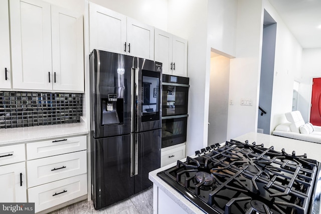 kitchen featuring black appliances, tasteful backsplash, and white cabinetry