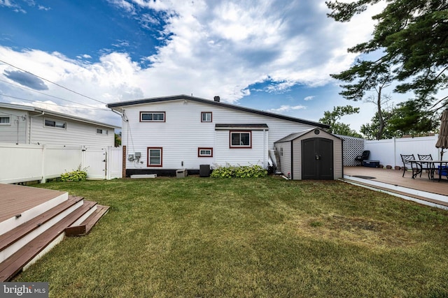 rear view of property with a shed, a yard, central air condition unit, and a wooden deck