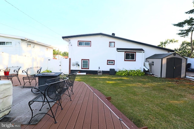 back of house with a wooden deck, a lawn, and a shed