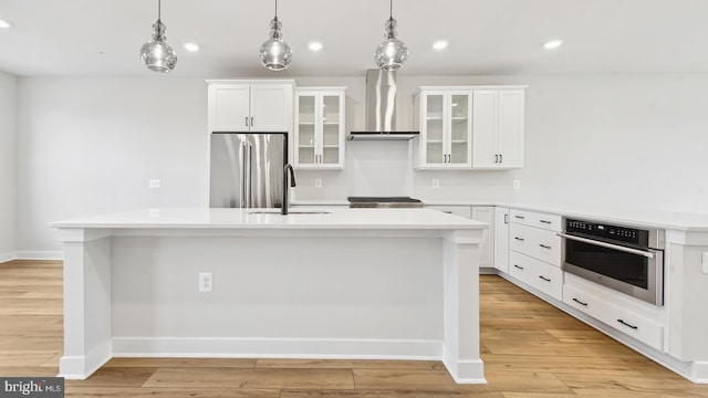 kitchen featuring appliances with stainless steel finishes, a center island with sink, and wall chimney exhaust hood