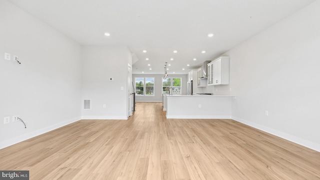 unfurnished living room with light wood-type flooring and sink