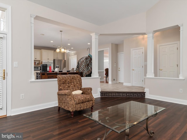 living area with a chandelier, wood-type flooring, decorative columns, and vaulted ceiling