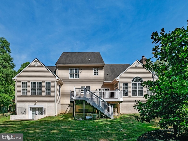 rear view of property featuring a lawn and a deck