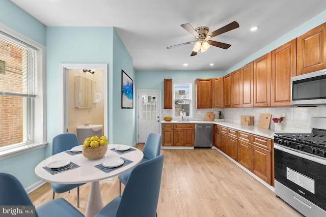 kitchen with light wood-type flooring, appliances with stainless steel finishes, sink, and a wealth of natural light