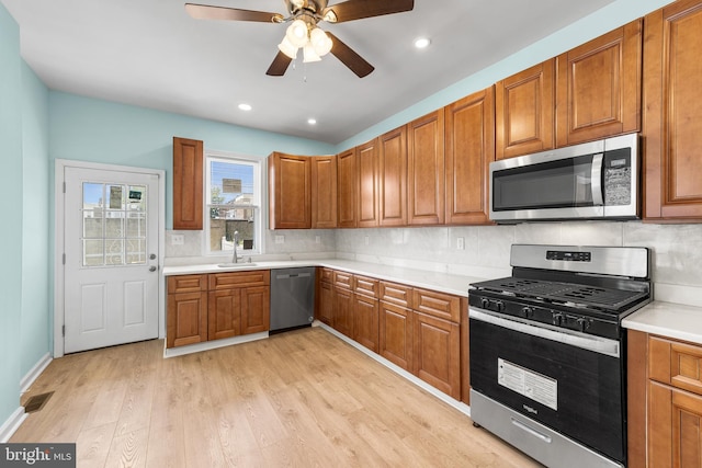 kitchen with sink, backsplash, ceiling fan, stainless steel appliances, and light wood-type flooring