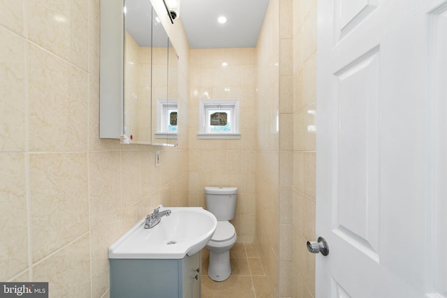 bathroom with vanity, toilet, tile patterned flooring, and tile walls