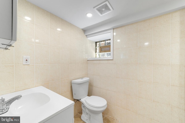 bathroom with vanity, tile walls, and toilet