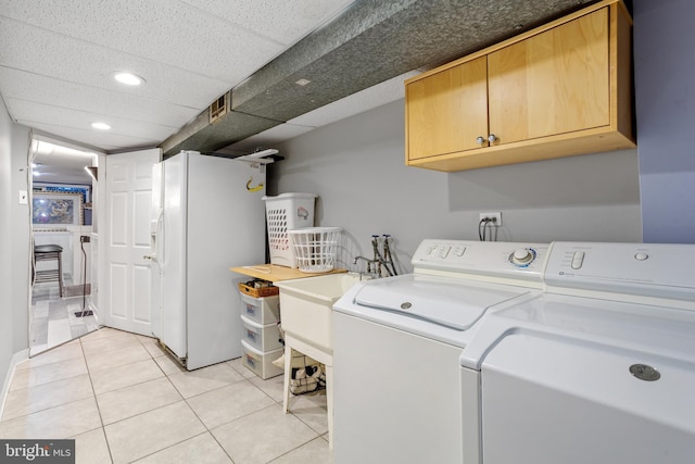 clothes washing area with washer and clothes dryer, light tile patterned flooring, and cabinets