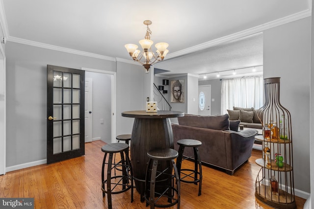 interior space with light wood-type flooring, an inviting chandelier, and ornamental molding