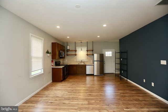 kitchen with a wealth of natural light, sink, appliances with stainless steel finishes, and light hardwood / wood-style flooring