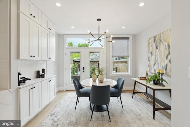 dining area with french doors, an inviting chandelier, and light hardwood / wood-style floors