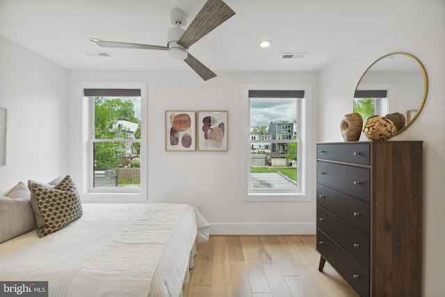 bedroom with ceiling fan, light hardwood / wood-style floors, and multiple windows