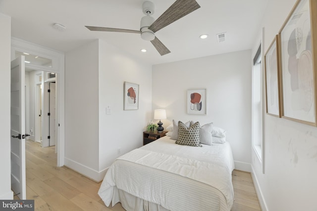 bedroom featuring ceiling fan, multiple windows, and light wood-type flooring