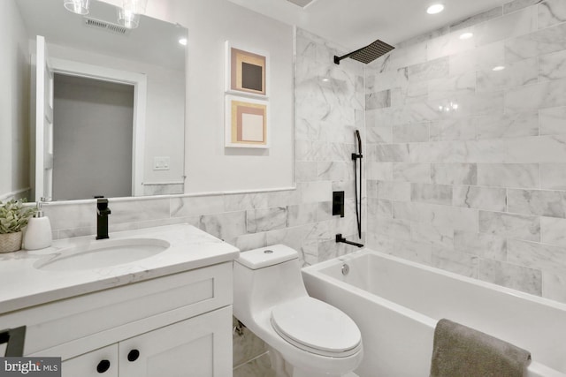 full bathroom featuring toilet, vanity, tile walls, and tiled shower / bath