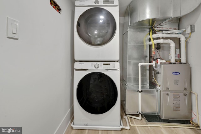 laundry area featuring wood-type flooring and stacked washer and dryer