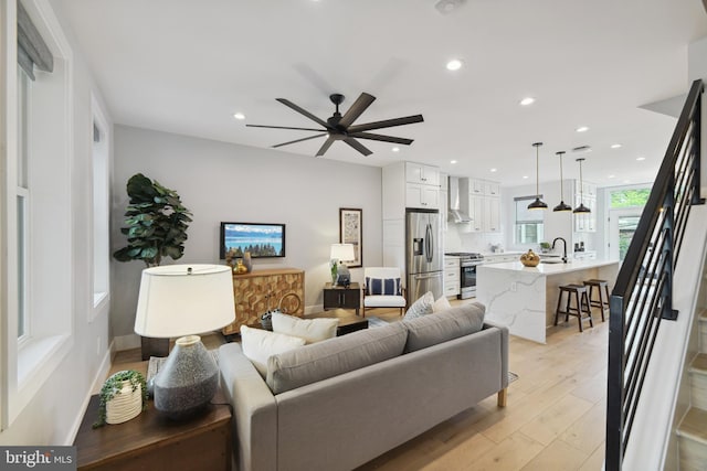 living room with ceiling fan, sink, and light hardwood / wood-style floors