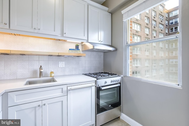 kitchen with white cabinets, stainless steel gas range, tasteful backsplash, and sink