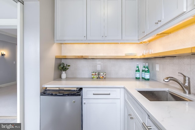 kitchen with light stone counters, sink, decorative backsplash, stainless steel dishwasher, and white cabinets