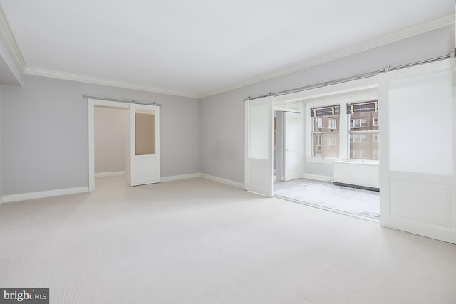 unfurnished room featuring ornamental molding, a barn door, and carpet floors