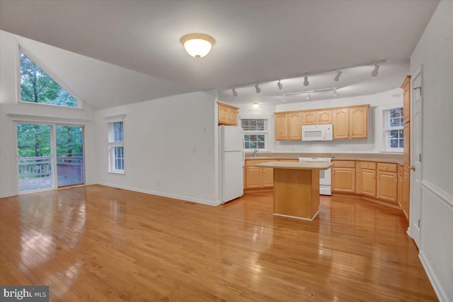 kitchen featuring light wood-type flooring, white appliances, sink, light brown cabinets, and a center island