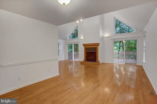 unfurnished living room featuring light wood-type flooring, high vaulted ceiling, and a wealth of natural light