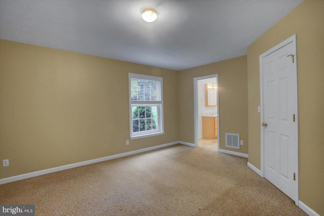 unfurnished bedroom featuring ensuite bath and light colored carpet