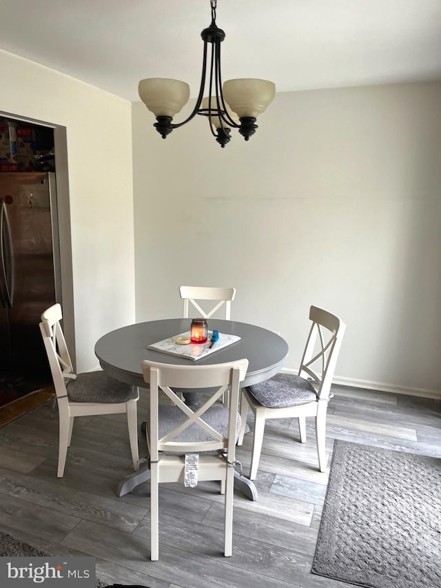 dining space with dark wood-type flooring and a notable chandelier