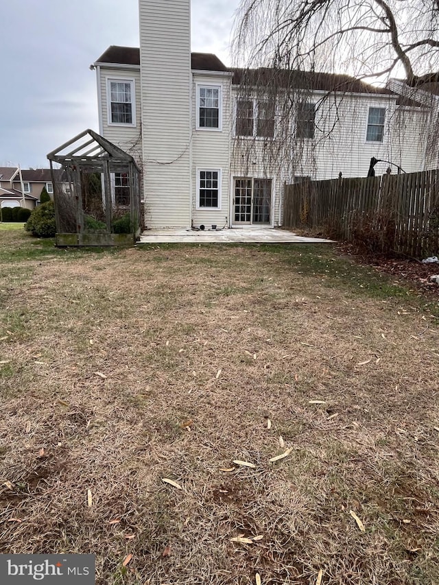 rear view of property with a pergola, a lawn, and a patio