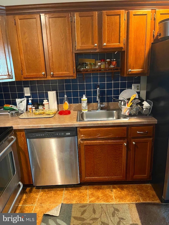 kitchen with decorative backsplash, stainless steel appliances, light tile patterned flooring, and sink